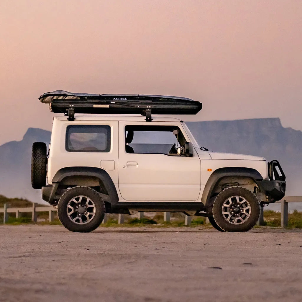 Tente de toit légère Alu-Cab LT-50 en aluminium, déployée sur un véhicule, avec matelas et fenêtre ouverte.