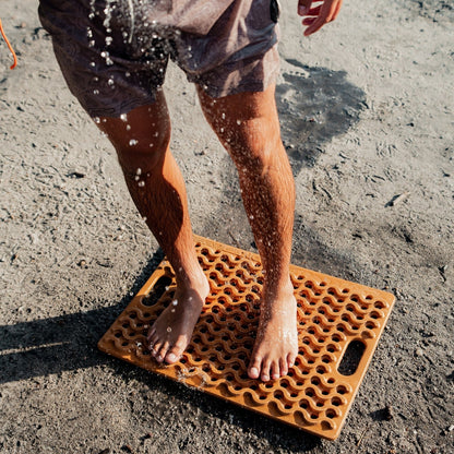 Tapis de douche extérieur ONTAP Mariner Mat beige pour camping et 4x4, avec jerrycan en arrière-plan.