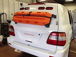 Support de plaques à sable Maxtrax N4 OFFROAD sur le hayon d'un Toyota HDJ100, accessoire tout-terrain robuste.