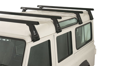 Kit de 4 barres de toit noires RHINO-RACK Heavy Duty 1500mm avec pieds pour Land Rover Defender 110 1993-2020, vue en extérieur.