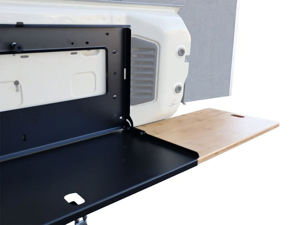 Table pliante de porte arrière Front Runner pour 4x4 offroad, surface en bois avec supports métalliques robustes.