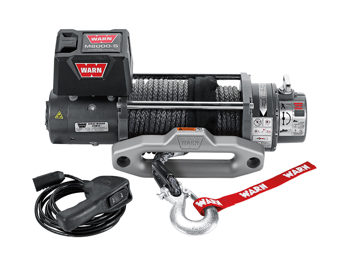Treuil Warn M8000 3629 kg 12V pour véhicule tout-terrain, avec câble robuste et commande électrique, en action.